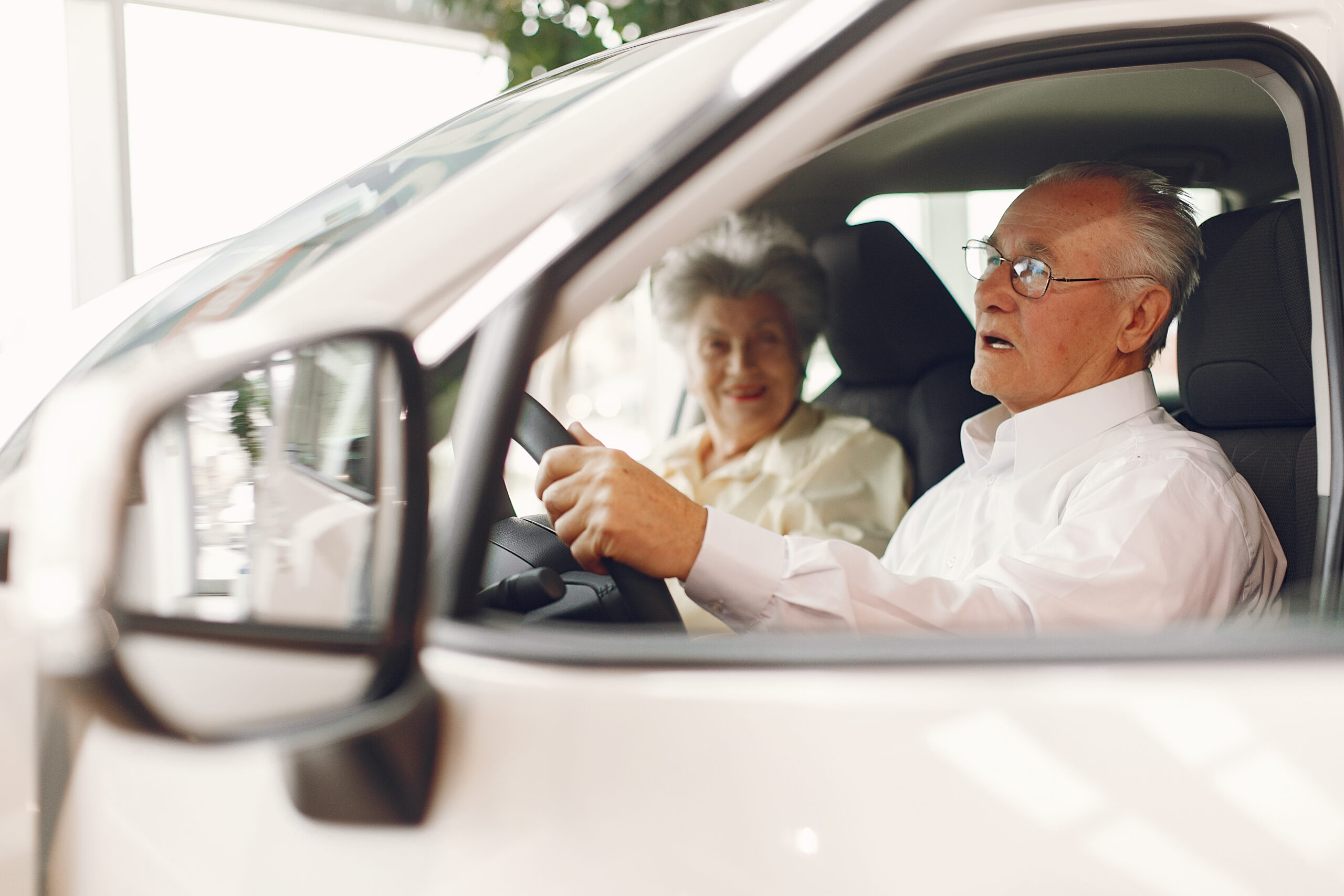 Senior volunteer gentleman driving a senior lady client to a medical appointment